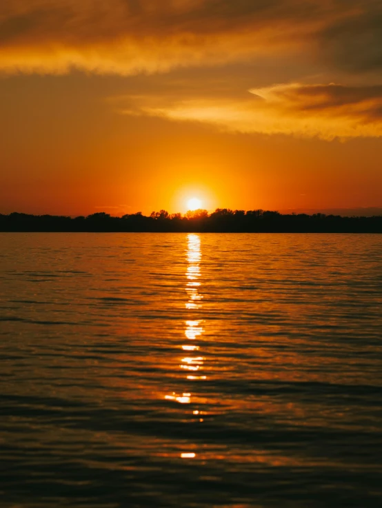 a large body of water with a sunset in the background