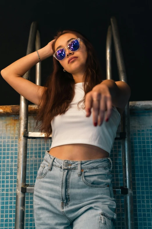 the girl in blue sunglasses is posing by a swimming pool