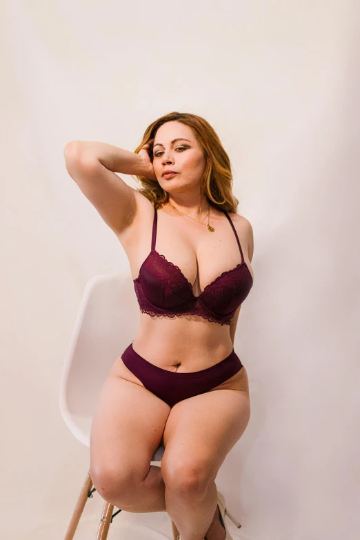 a woman in maroon lingerie sitting on a chair