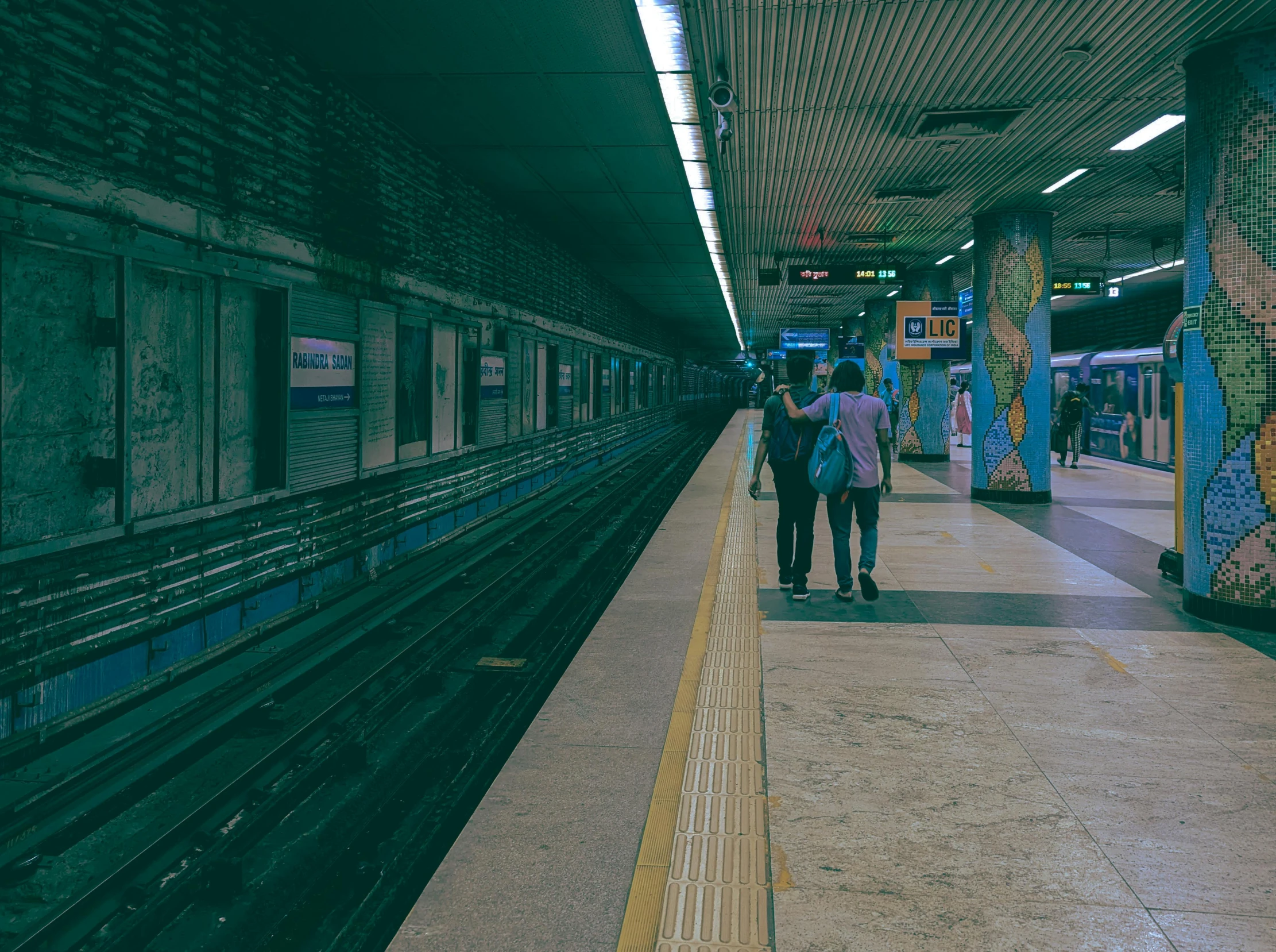 two people in a subway station waiting for the train