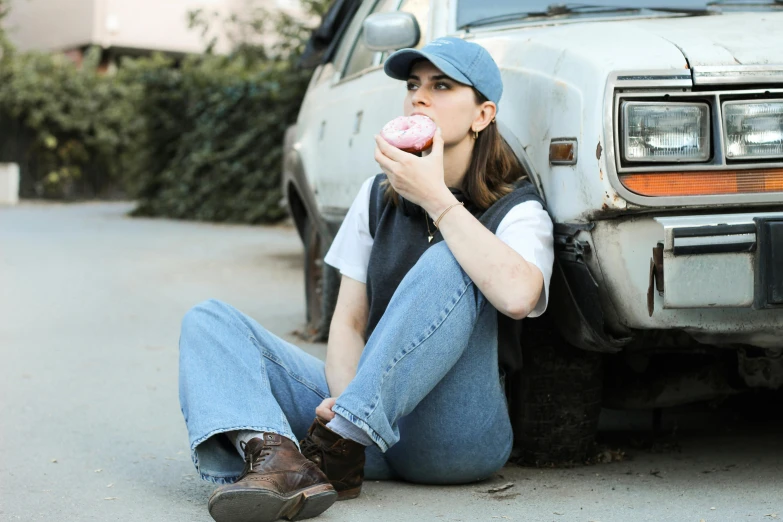 the woman is eating a pink doughnut out of her hand