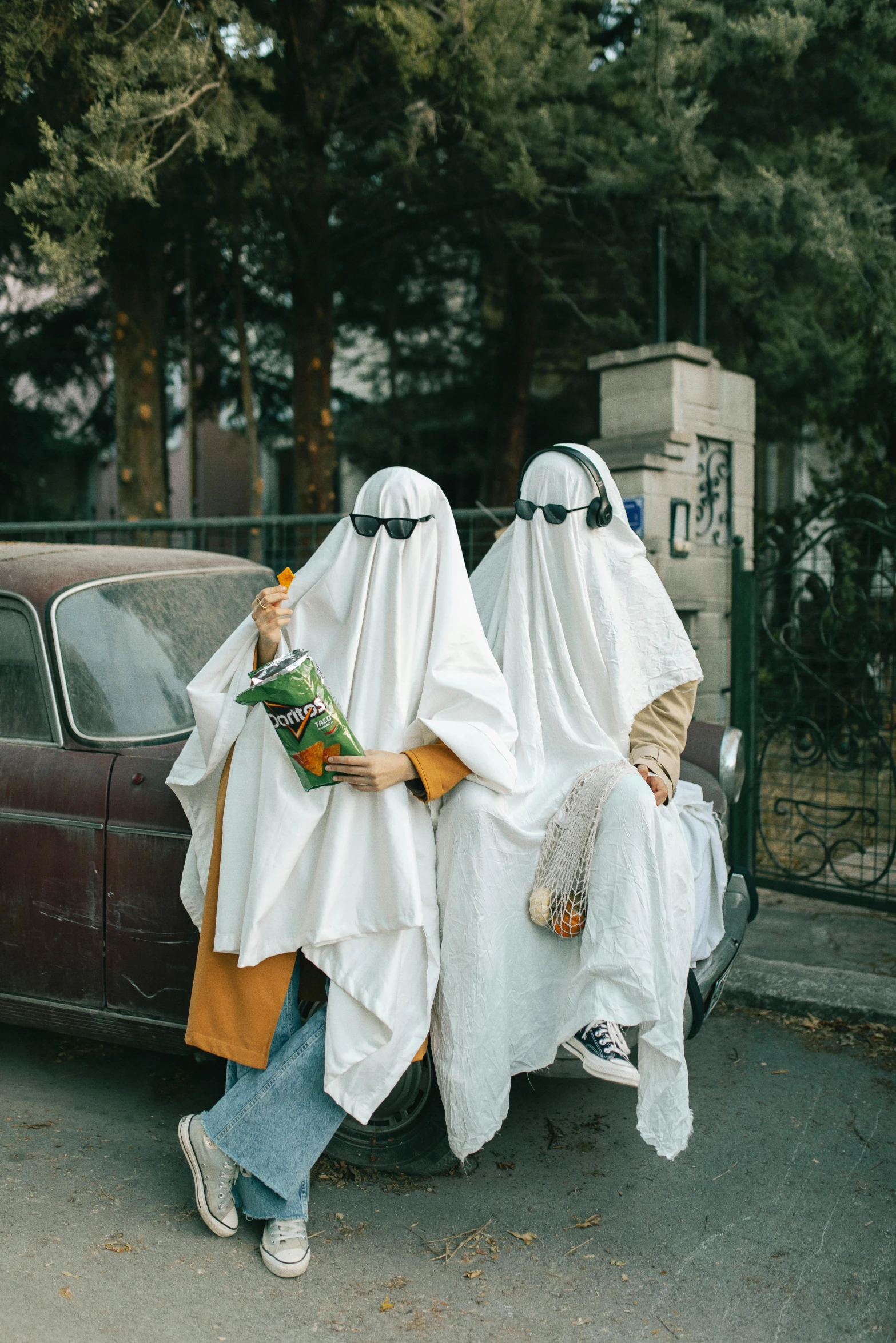 two women in white covered clothing are sitting on the hood of a car