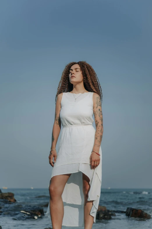 a woman stands by the water looking up