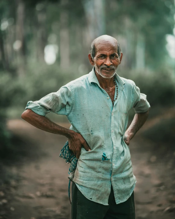 an old man stands in the middle of a dirt road