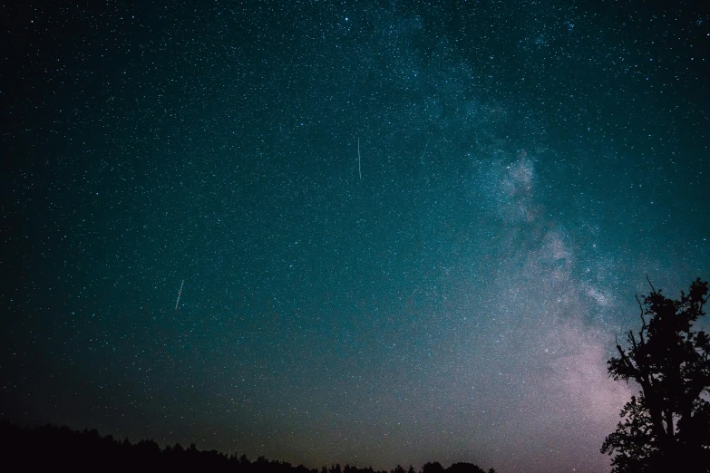 a night sky with many stars above a hill