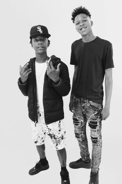 two young men pose for the camera in their jeans and shoes