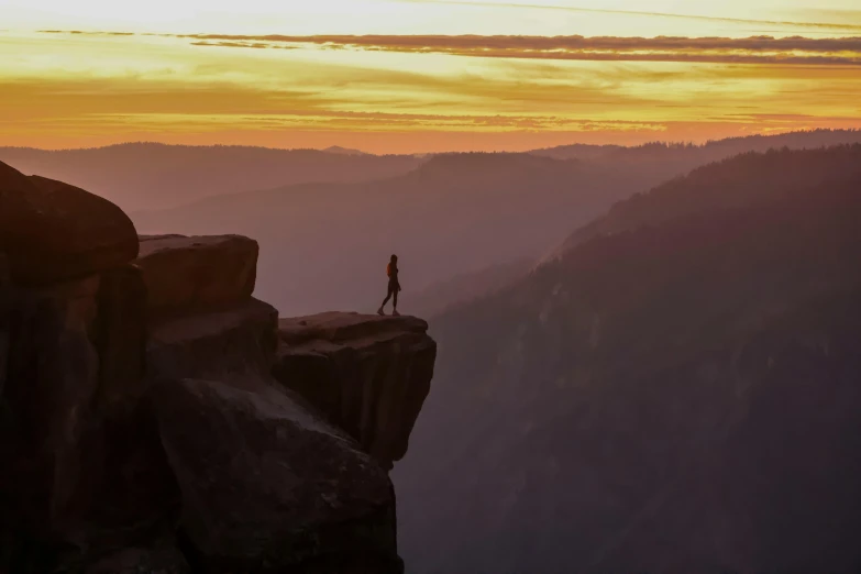 a person stands on a cliff overlooking the mountains