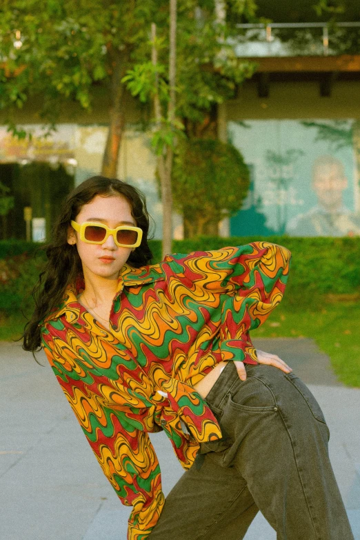 a woman in sunglasses and colorful shirt posing with her leg up