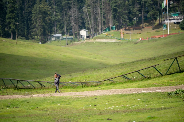 a man walking across a lush green hillside