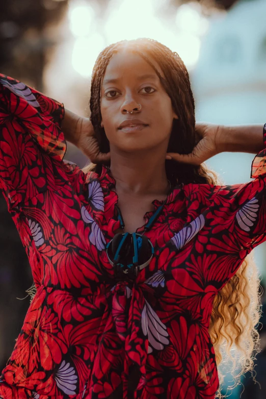 a woman stands with her hands behind her head