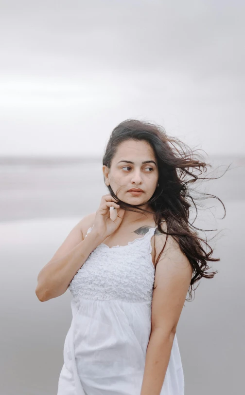 a woman in a white dress with the ocean in the background