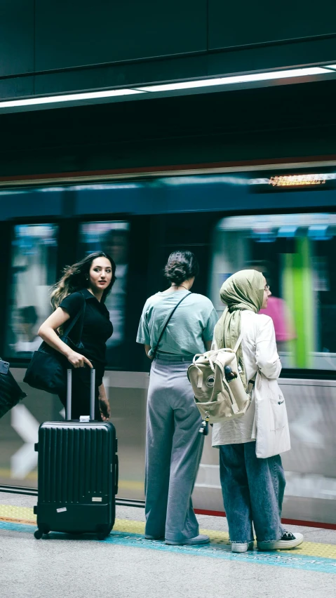 people standing around at the train station with their luggage