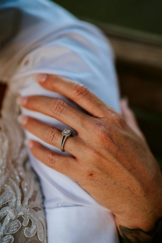 a woman holding her hand with a gold wedding ring