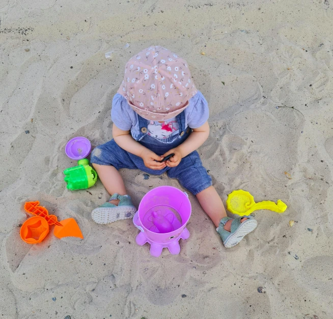 a toddler plays in the sand with his toys