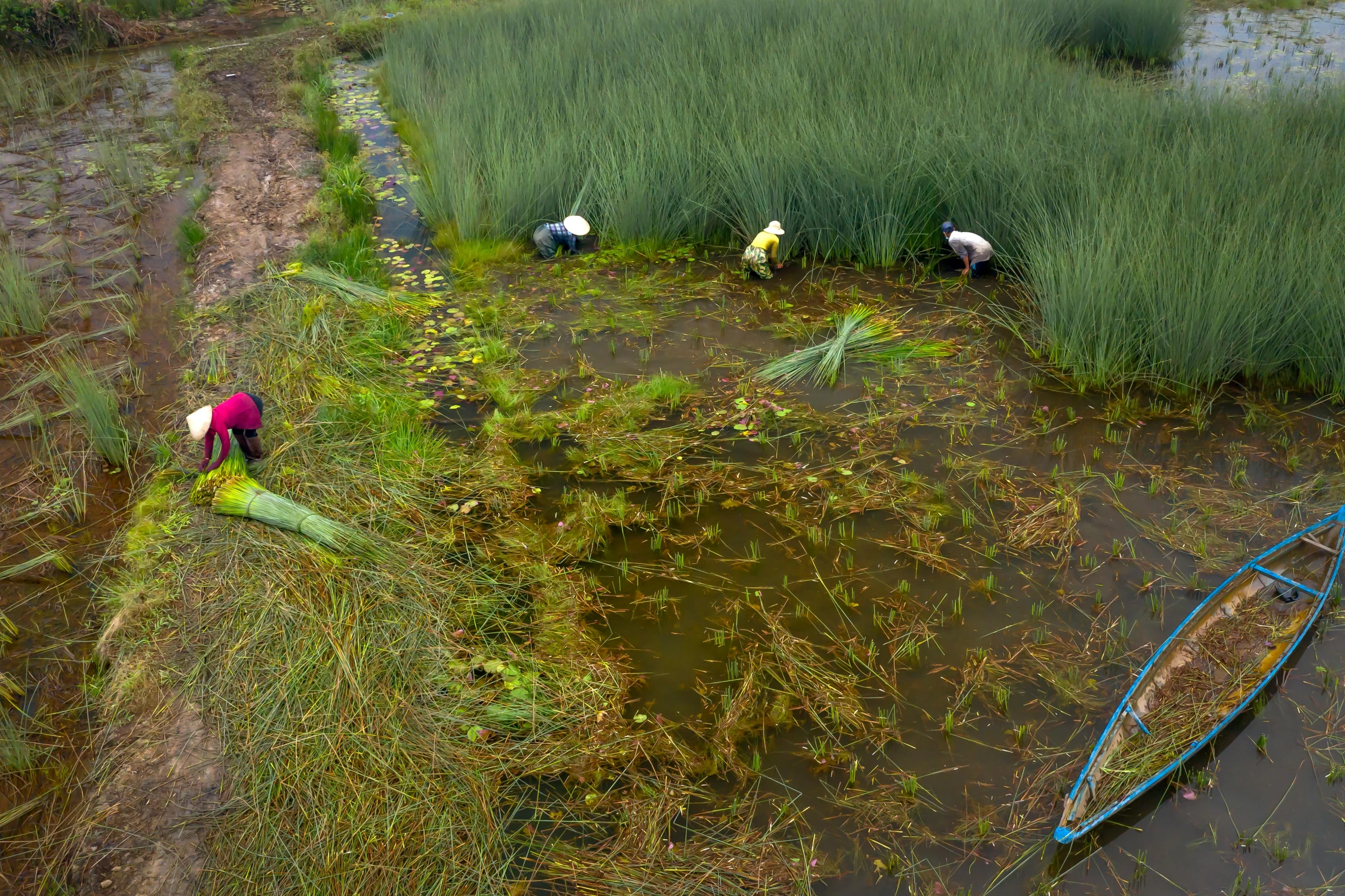 three people standing in the mud in front of a boat