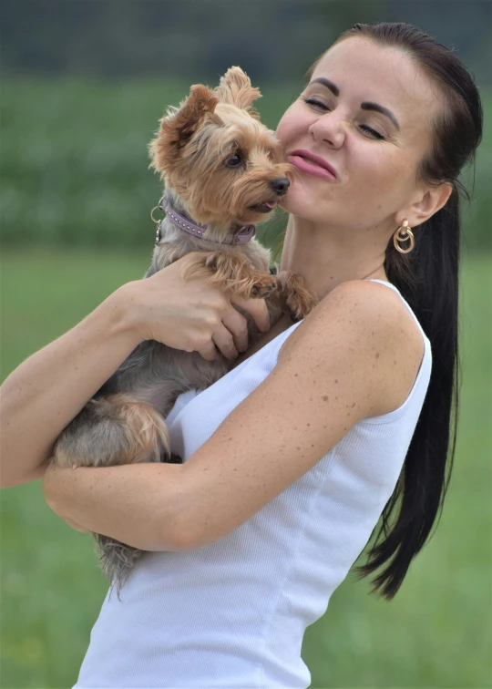 a woman in white holding a small brown dog