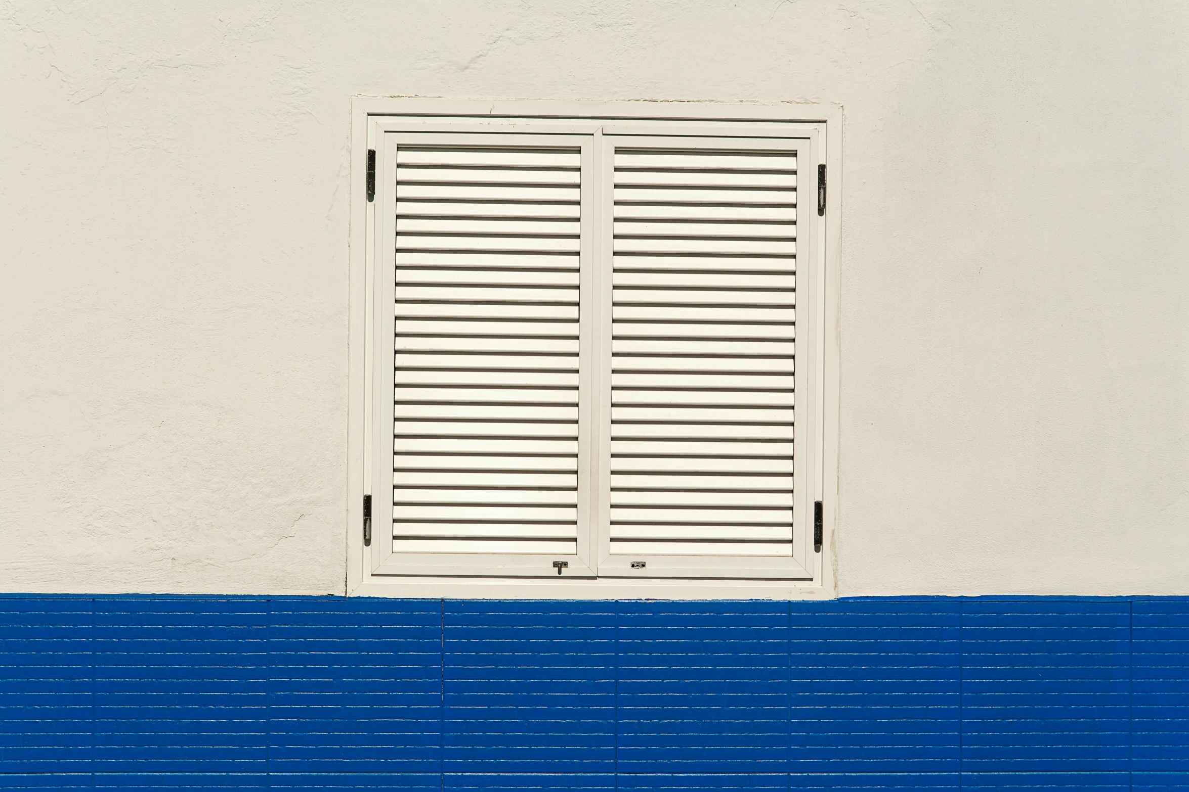 two closed white wooden doors on top of a white building