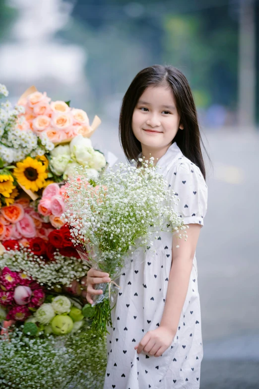 a little girl holds flowers by a fountain