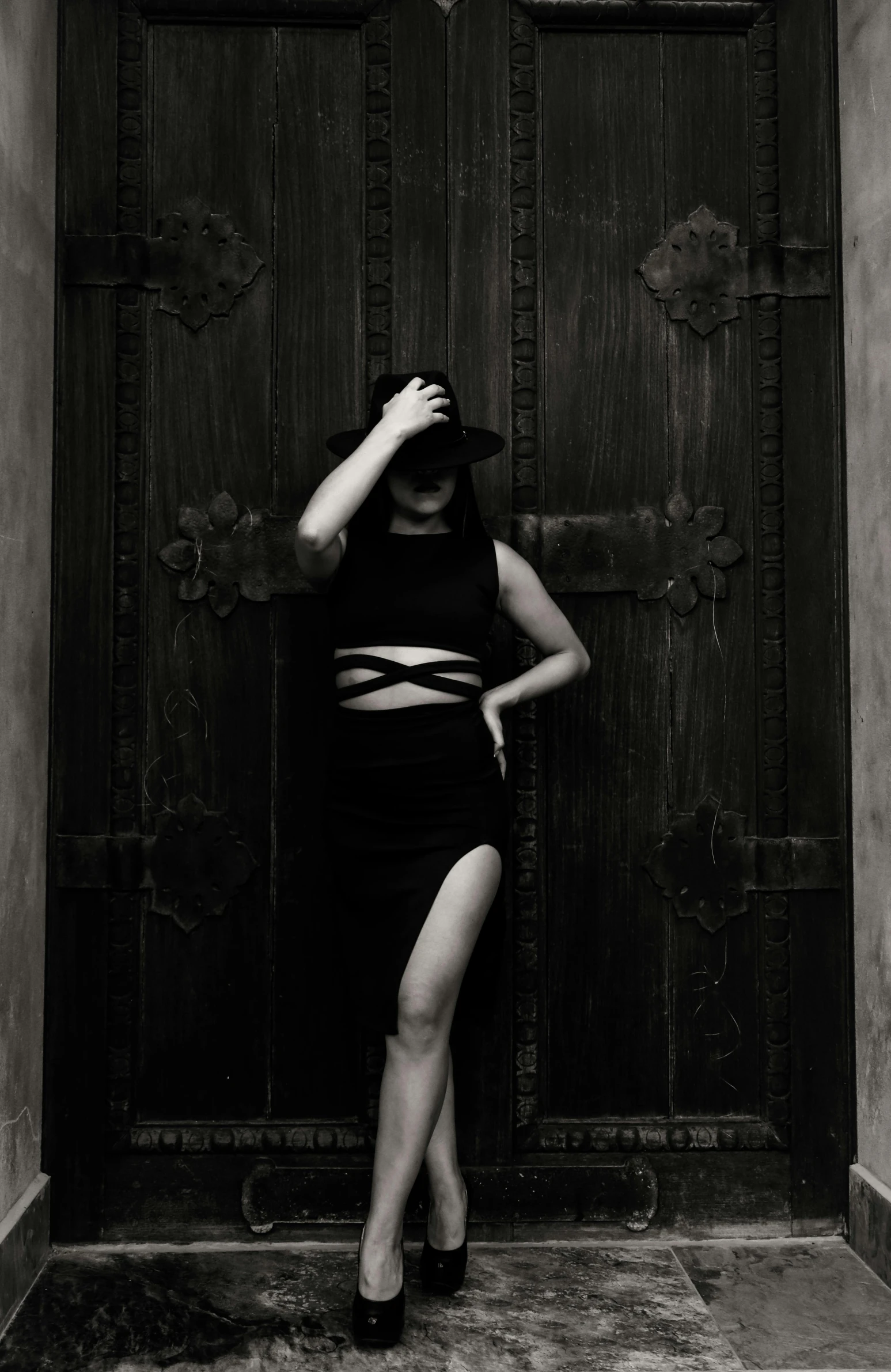 black and white pograph of a woman posing in front of a wooden door