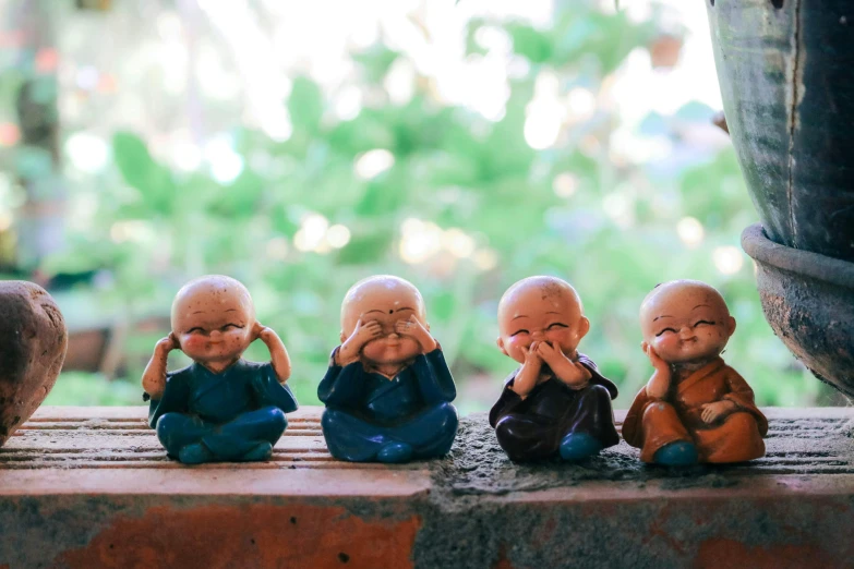 a line of small plastic buddha statues sitting on top of a wooden bench