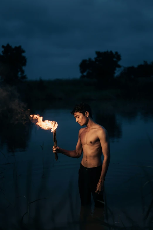 the man is standing in the water holding a small fire