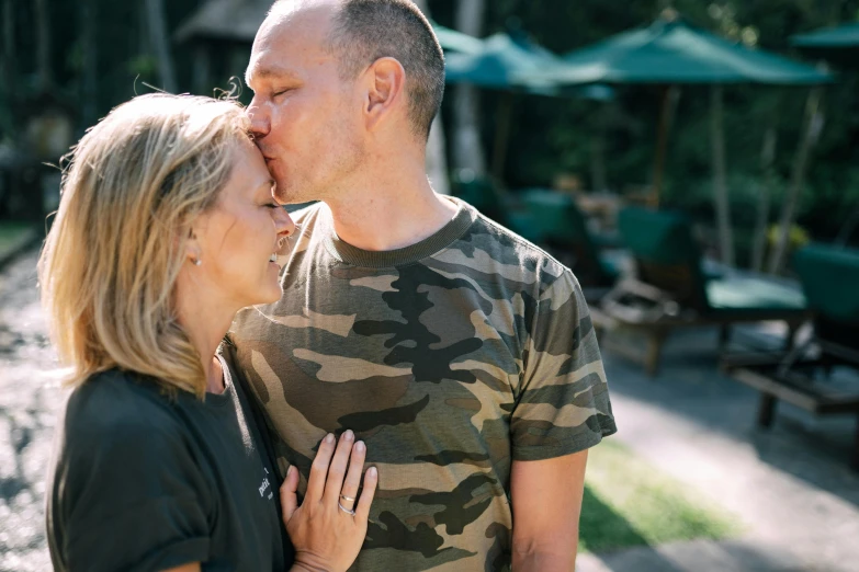 a man is kissing a woman while they stand together