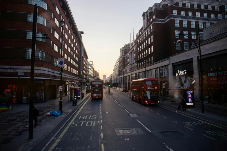 two busses on a city street at dusk