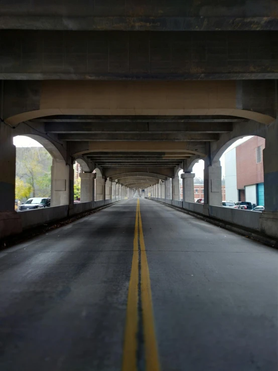 the street underneath an overpass is lined with cars