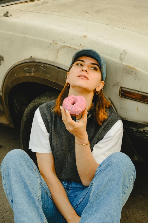 the woman is eating the donut sitting on the ground