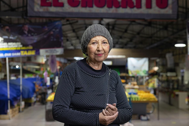 an elderly woman stands next to a shop entrance