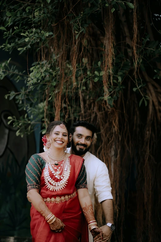 an indian couple standing near a tree on their wedding day