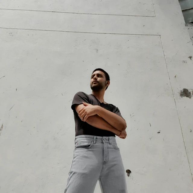 man with arms crossed in front of white building