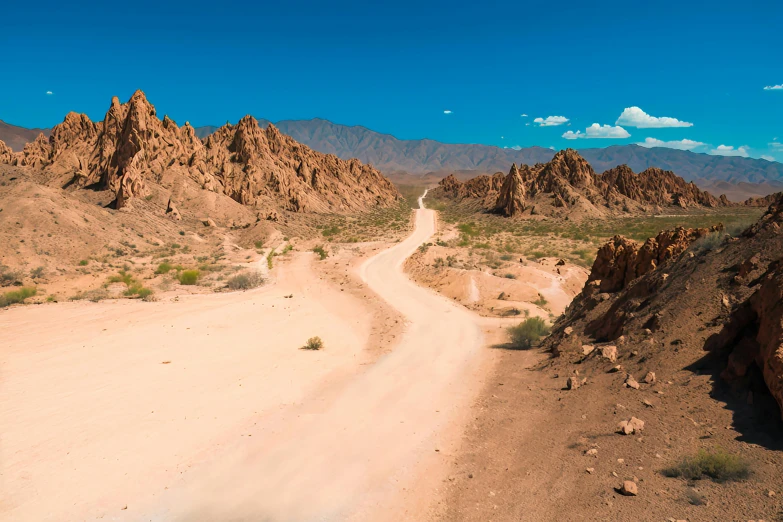 a dirt road in the desert with large rocks on either side