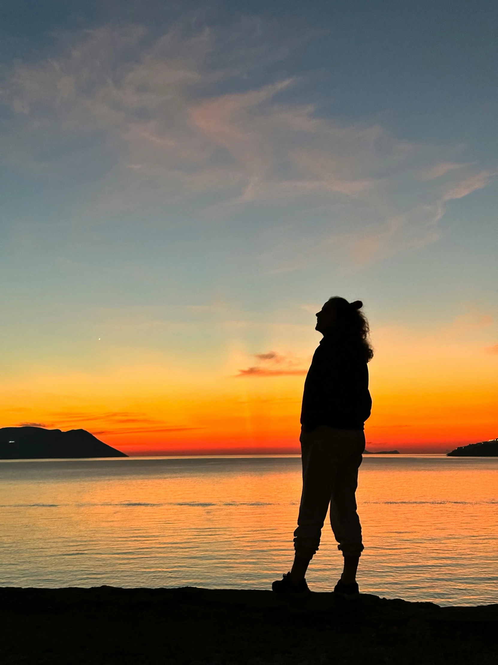 the woman is silhouetted against a sunset on the ocean