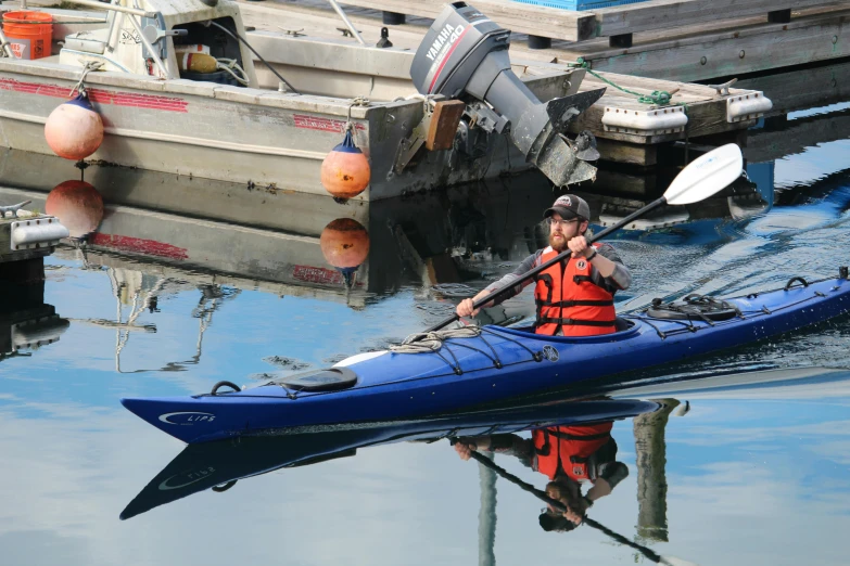 a man on a blue kayak in front of some docks