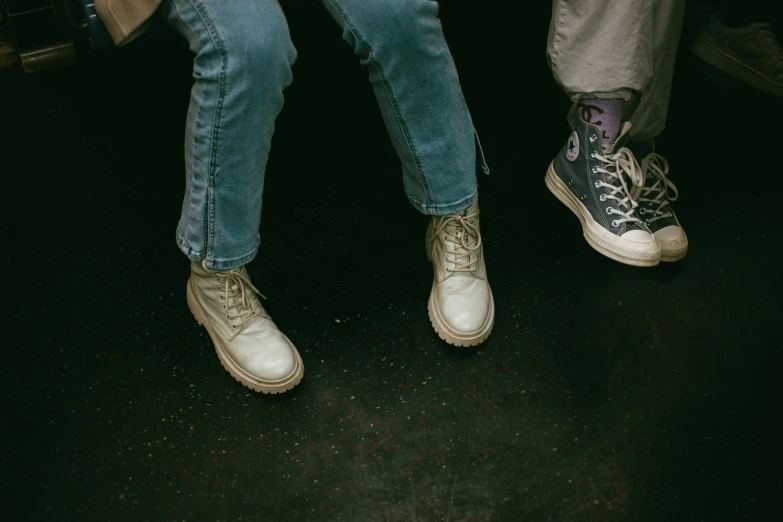 a closeup of legs wearing worn lace - up tennis shoes