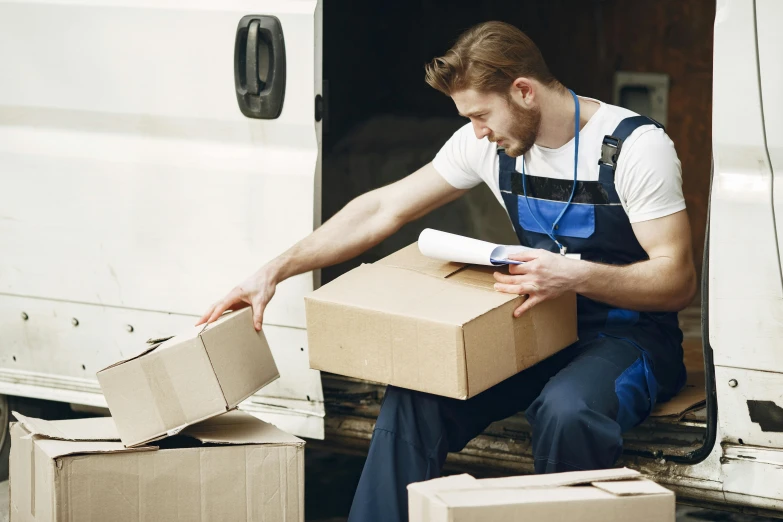 a delivery man in overalls loads a box