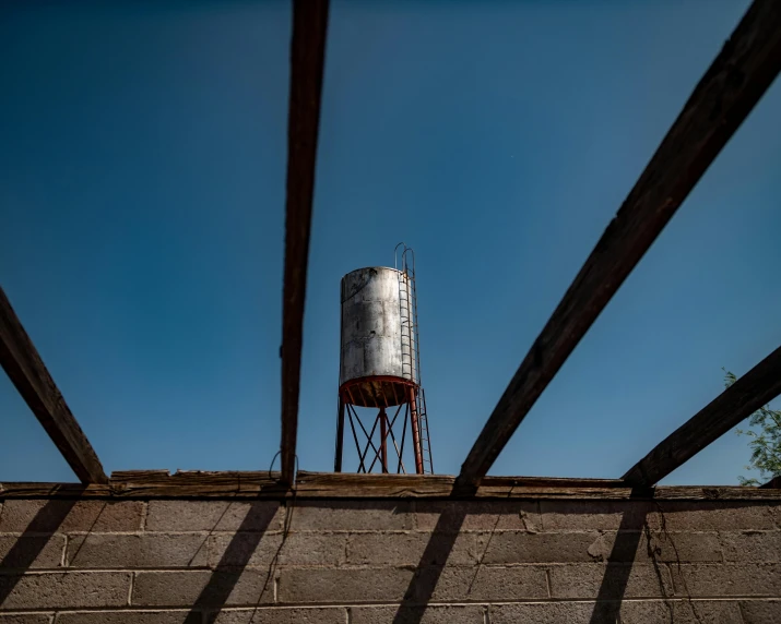 a water tower from below on a brick wall