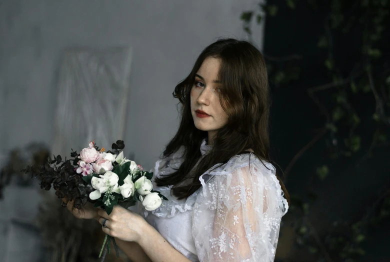 woman in sheer dress holding flowers looking at the camera