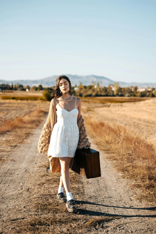 a woman in a short white dress holding a suitcase