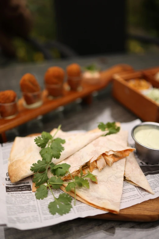 a plate with some green herbs and sauces next to some quesadillas