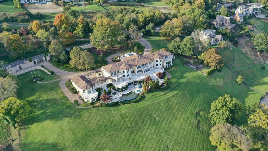 an aerial view of a huge home surrounded by a lush green field