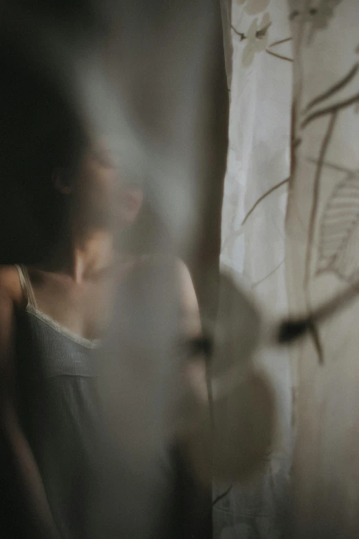 a woman leaning against a wall behind curtains