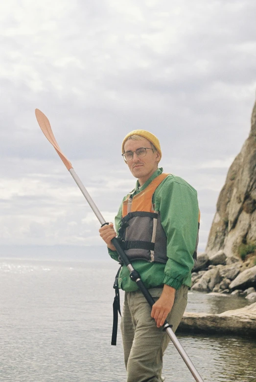 a man is standing on rocks with a paddle