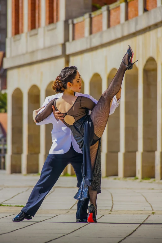 the woman is posing and stretching up in the street