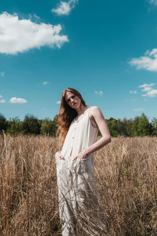 a woman poses on a field with grass