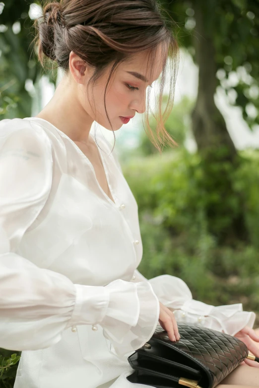 a woman is holding her purse in a forest