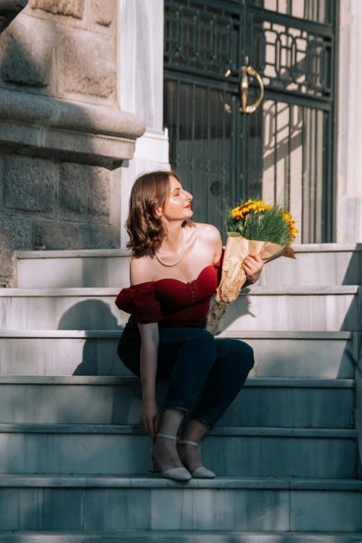 a lady that is sitting on some stairs with flowers