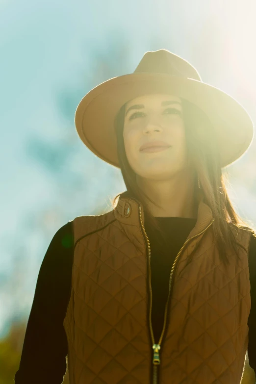 a woman with a hat and jacket and sunlight streaming through her face