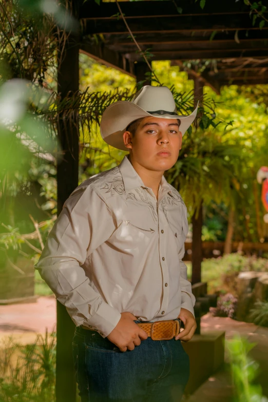 a boy standing under a shade house in a cowboy hat